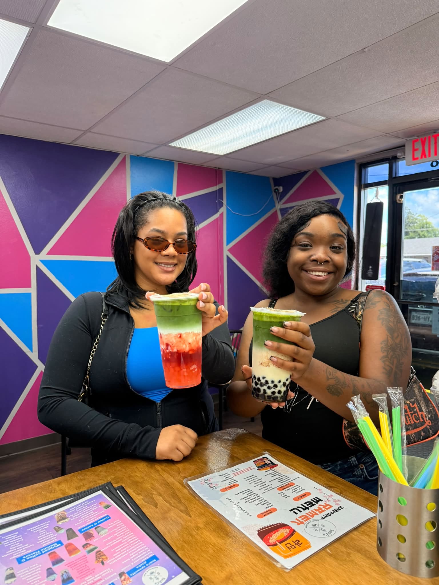 Two visitors holding matcha drinks inside Suki’s colorful shop.